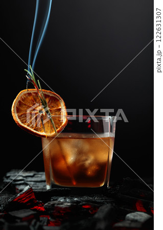 Whiskey with ice, orange slice, and burning rosemary. 122631307