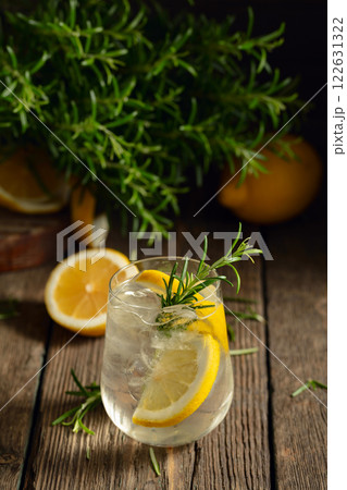Cocktail gin tonic with ice, lemon, and rosemary on a old wooden table. 122631322