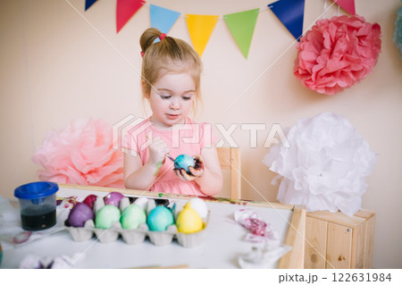 Cute girl painting Easter eggs in bright colourful room Cute girl painting Easter eggs in bright colourful room 122631984
