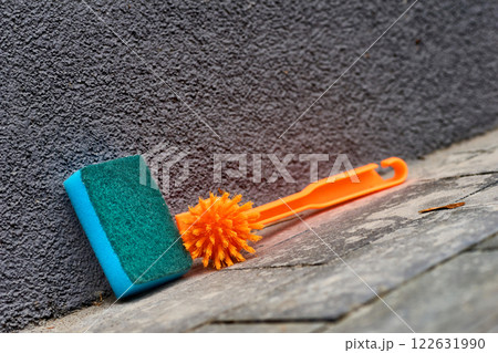 Orange brush green sponge for cleaning on gray plastered wall Orange brush green sponge for cleaning on gray plastered wall 122631990