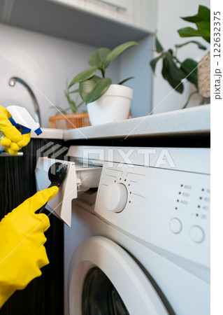 Housekeeper cleaning the kitchen, using cleaning products and wearing protective gloves for a thorough and safe home cleaning process. Housekeeper cleaning the kitchen, using cleaning products and wearing protective gloves for a thorough and safe home cleaning process. 122632375