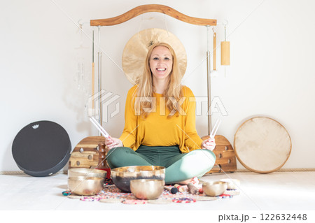 Young cheerful woman performing music therapy session with traditional instruments. Sound meditation, body healing. Seven chakras. Healthcare recreation process Young cheerful woman performing music therapy session with traditional instruments. Sound meditation, body healing. Seven chakras. Healthcare recreation process 122632448