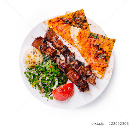 Delicious grilled skewers served with flatbread and fresh vegetables in a vibrant setting 122632508