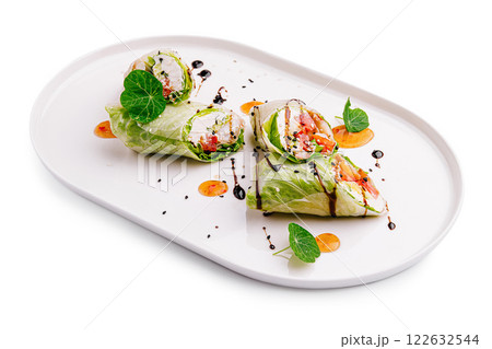 Fresh vegetable rolls displayed elegantly on a white plate with vibrant garnishes and drizzles 122632544