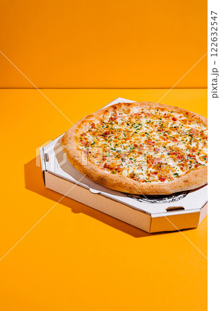 Delicious pizza with a golden crust and toppings on a vibrant yellow background Delicious pizza with a golden crust and toppings on a vibrant yellow background 122632547