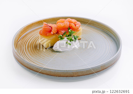 Savory dish featuring salmon on a textured plate with creamy dressing and fresh herbs Savory dish featuring salmon on a textured plate with creamy dressing and fresh herbs 122632691