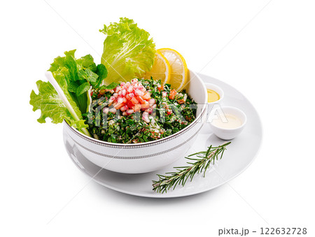 Fresh tabbouleh salad made with parsley, tomatoes, and lemon served in a stylish bowl on a white plate 122632728