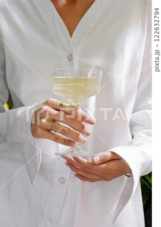Elegant drink served outdoors while wearing a white shirt with beautiful accessories in a bright setting Elegant drink served outdoors while wearing a white shirt with beautiful accessories in a bright setting 122632794