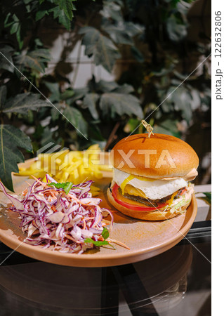 Delicious burger served with fresh salad and crispy fries on a warm afternoon Delicious burger served with fresh salad and crispy fries on a warm afternoon 122632806