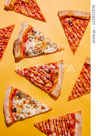 Delicious slices of various pizza flavors arranged on a vibrant yellow background for a colorful culinary display Delicious slices of various pizza flavors arranged on a vibrant yellow background for a colorful culinary display 122632836