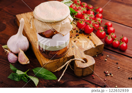 Delicious homemade preserves with garlic, tomatoes, and basil arranged on a rustic wooden board Delicious homemade preserves with garlic, tomatoes, and basil arranged on a rustic wooden board 122632939