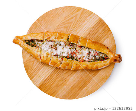 Traditional Turkish pide with filling served on a wooden platter in a cozy restaurant setting 122632953