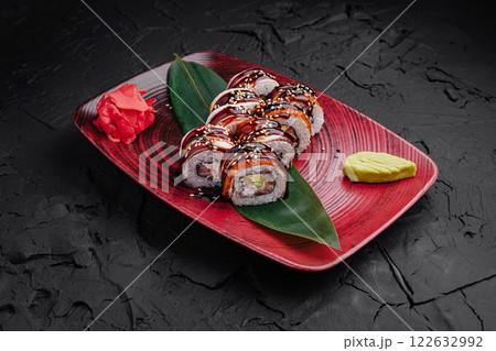 Sushi platter featuring assorted rolls garnished with wasabi and pickled ginger on a vibrant red plate Sushi platter featuring assorted rolls garnished with wasabi and pickled ginger on a vibrant red plate 122632992
