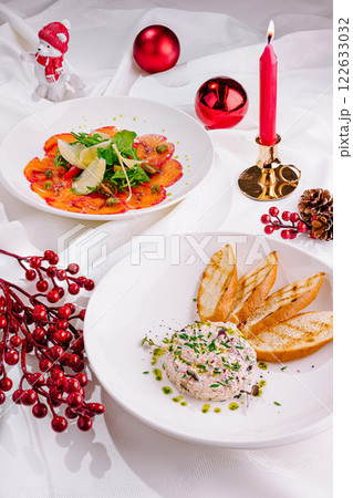 Holiday dinner table featuring colorful appetizer plates and festive decor with candlelight 122633032