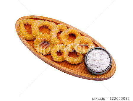 Crispy onion rings served with a tangy dipping sauce on a wooden platter in a casual dining setting Crispy onion rings served with a tangy dipping sauce on a wooden platter in a casual dining setting 122633053