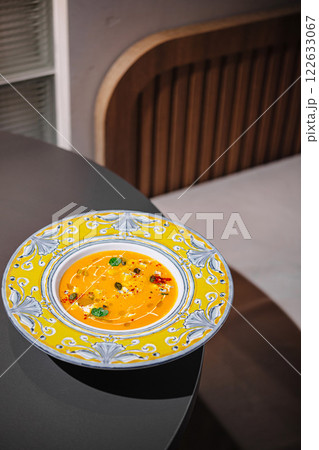 Delicious bowl of vibrant soup served in an artistic plate on a sleek table in a modern dining room setting 122633067