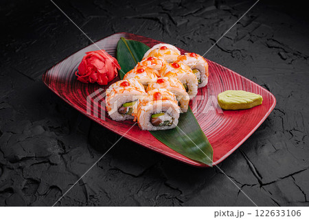 Delicious sushi rolls beautifully presented on a vibrant plate with a touch of greenery and garnishes 122633106