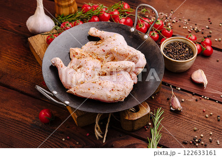 Preparing a flavorful marinated chicken ready for grilling with fresh herbs and spices set on a rustic wooden surface Preparing a flavorful marinated chicken ready for grilling with fresh herbs and spices set on a rustic wooden surface 122633161