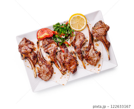 Grilled lamb chops served with fresh herbs and lemon on a clean white plate Grilled lamb chops served with fresh herbs and lemon on a clean white plate 122633167