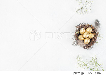 golden Easter quail eggs in the nest with blossoms spring flowers for greeting text. Happy Easter. top view. copy space 122633875