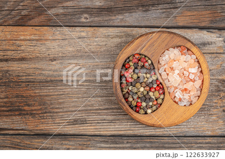 A variety of Natural Spices pepper peas and pink Salt in a Rustic Bowl on a Wooden Table Top view. Free copy space 122633927