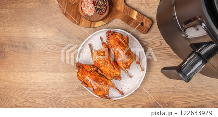 roasted quails with from the hot air fryer oven on a wooden background. top view. copy space 122633929