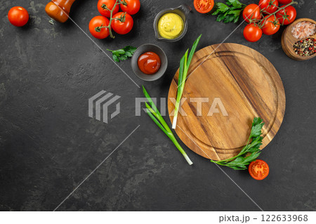 round wooden cutting board with edging. cherry tomatoes and spices on a dark background. mockup with copy space top view round wooden cutting board with edging. cherry tomatoes and spices on a dark background. mockup with copy space top view 122633968