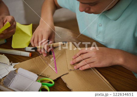 Young student engaging in crafts with recycled cardboard and measuring tools Young student engaging in crafts with recycled cardboard and measuring tools 122634651