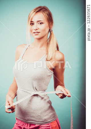 Fitness girl measuring her waistline Fitness girl measuring her waistline 122635671