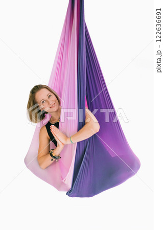 Fit smiling woman in black workout suit practicing fly yoga stretching in hammock 122636691