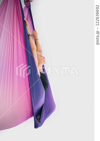 Fit smiling woman in black workout suit practicing fly yoga stretching in hammock 122636692