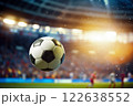 A soccer ball is in the air, surrounded by players on a field 122638552