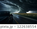 Tornado in a field in the USA with car on road in field under stormy dark sky 122638554