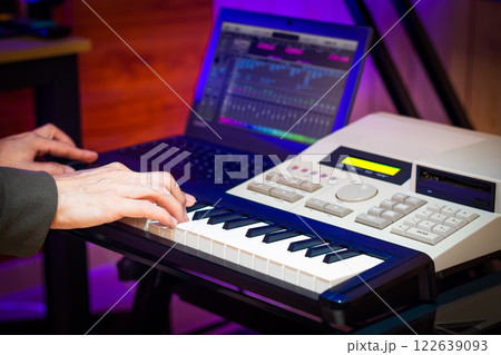 male professional music producer, composer, arranger hands playing on midi keyboard keys with music sequencer in home studio. music production 122639093