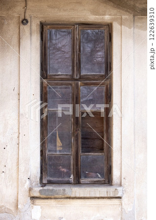 Old wooden window with broken glass on the wall of an abandoned house 122639310