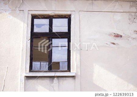 Old wooden window with broken glass on the wall of an abandoned house 122639313