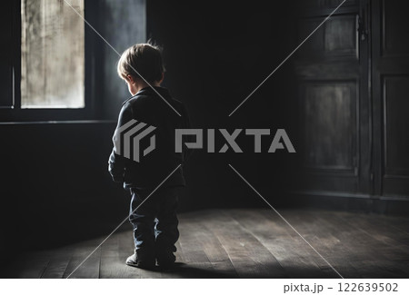 暗い家の中でうつむいている男の子の後ろ姿 122639502