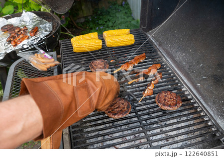 Barbecue grill with burgers, skewers, and corn being cooked outdoors. Barbecue grill with burgers, skewers, and corn being cooked outdoors. 122640851