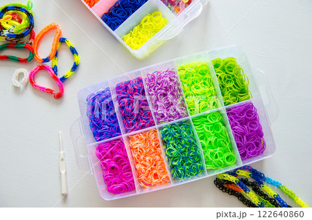 Box of colorful loom bands and bracelets on white table. Box of colorful loom bands and bracelets on white table. 122640860