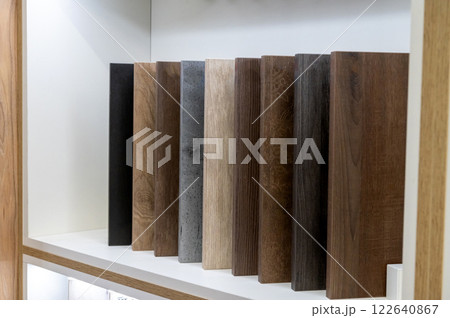 Wooden plank samples in various shades arranged on a shelf for interior design. 122640867