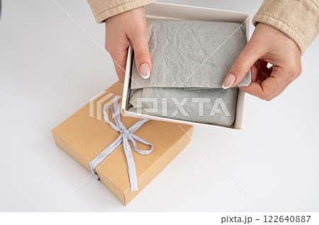 Female hands opening gift box with bow. National Cartonnage Day 122640887