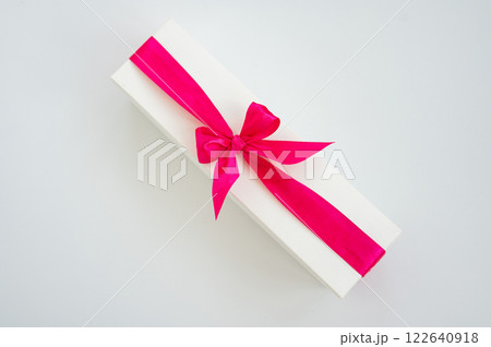 Elegant white gift box with bright pink ribbon bow on minimalistic background Elegant white gift box with bright pink ribbon bow on minimalistic background 122640918