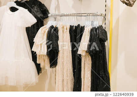 Elegant black and white dresses displayed on clothing rack in boutique. National Thrift Shop Day Elegant black and white dresses displayed on clothing rack in boutique. National Thrift Shop Day 122640939