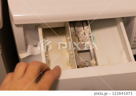 Woman opening container of washing machine with mold, dirt and limescale.  122641071