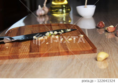 Chopped garlic on a cutting board next to a knife. Making a recipe for garlic butter. Cutting vegetables 122641324
