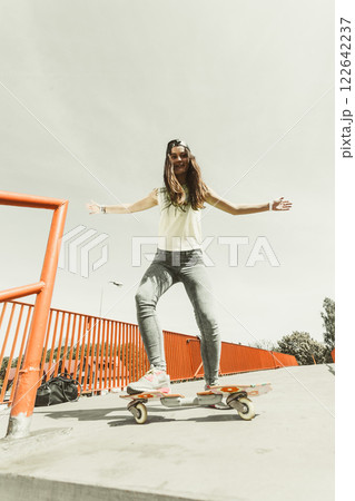 Teen girl skater riding skateboard on street. 122642237