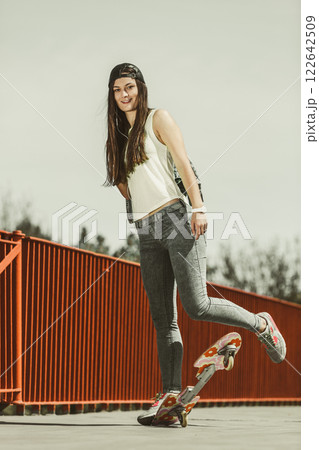 Teenage girl skater riding skateboard on street. 122642509
