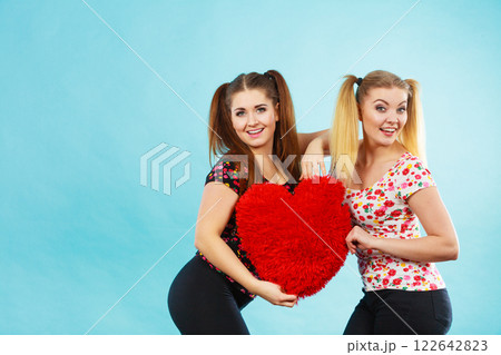 Happy two women holding heart shaped pillow 122642823