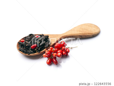 Dried tea in wooden spoon and barberries fruits on white backgrounds Dried tea in wooden spoon and barberries fruits on white backgrounds 122643556