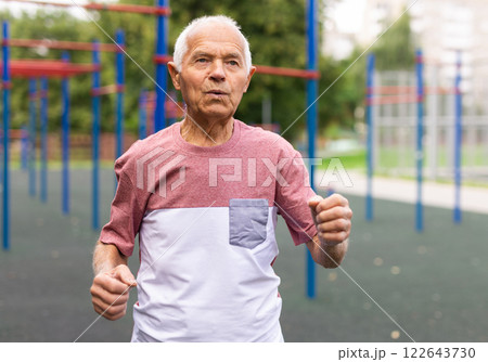Elderly man with grey hair running in the park 122643730